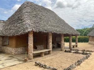 a hut with a thatched roof on a beach at ShambaZuri in Gede