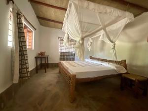 a bedroom with a bed with a canopy at ShambaZuri in Gede
