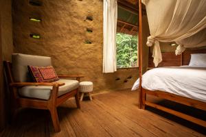 a bedroom with a bed and a chair and a window at Chirapa Manta Amazon Lodge in Lamas