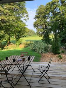 una mesa de picnic y sillas en una terraza de madera en Cabane chic et romantique SEMILLON près de Bordeaux, en Saint-Sulpice-et-Cameyrac