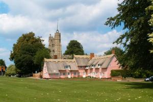 una gran casa rosa con una torre en un campo en Romney, a cosy Victorian cottage in a picturesque Suffolk village, en Cavendish
