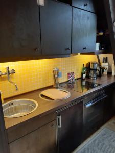 a kitchen with a sink and a yellow tile wall at Waldhaus in Kerschenbach