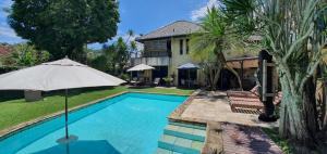 Una piscina con una sombrilla al lado de una casa. en REB Casa Itanhangá, en Río de Janeiro