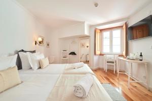 a white bedroom with two beds and a desk at Casa do Mercado Lisboa in Lisbon