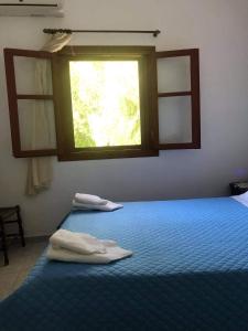a bedroom with two towels on a bed with a window at Pericles Traditional Cretan Home in Stavrokhórion