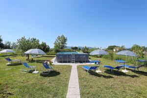 un groupe de chaises et de parapluies dans un champ dans l'établissement "La Casa di Carla", Lucca countryside, with private swimming pool and garden, à Capannori