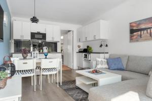 ein Wohnzimmer und eine Küche mit einem Sofa und einem Tisch in der Unterkunft Semesterboende på Hällestrand, Strömstad in Strömstad
