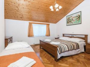 2 letti in una camera da letto con soffitto in legno di Apartments Emil a Brseč (Bersezio)