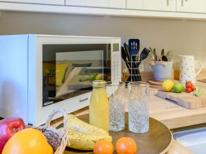 a microwave on a counter with fruit and a glass of orange juice at Claridge House in Lingfield