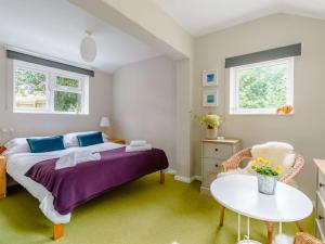 Schlafzimmer mit einem Bett, einem Tisch und Fenstern in der Unterkunft Claridge House in Lingfield