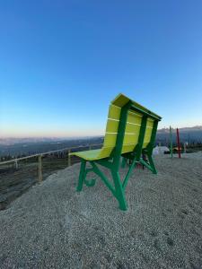 una sedia verde e gialla seduta in cima a una collina di Albergo Castiglione Langhe a Castiglione Tinella