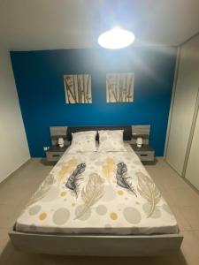 een slaapkamer met een bed met een blauwe muur bij Joli appartement rénové à neuf in Baie-Mahault