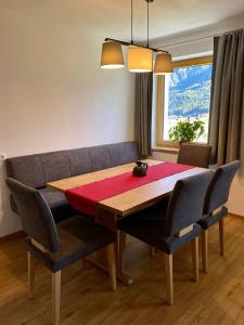 einen Esstisch und Stühle mit einem Tisch und einem Fenster in der Unterkunft Ferienwohnung Trattner in Bramberg am Wildkogel