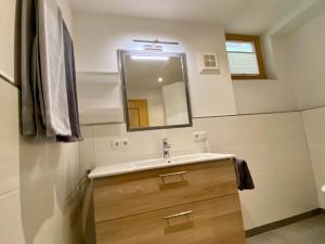 ein Bad mit einem Waschbecken und einem Spiegel in der Unterkunft Ferienwohnung Trattner in Bramberg am Wildkogel