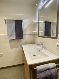ein Badezimmer mit einem Waschbecken, einem Spiegel und Handtüchern in der Unterkunft Ferienwohnung Trattner in Bramberg am Wildkogel