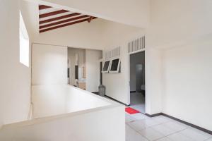a living room with white walls and white tile floors at RedDoorz Plus @ Pakuan Residence Tajur in Bogor