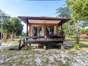 une petite maison avec une terrasse couverte dans un champ dans l'établissement Pura Vita Resort, à Koh Rong