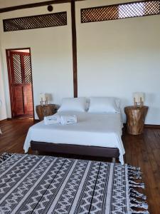 a bedroom with a white bed with a black and white rug at Hotel Playa Mandala in Palomino