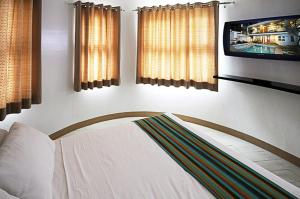 a bedroom with a bed and a tv and windows at Bluewaves Westcliff Villa in Boracay