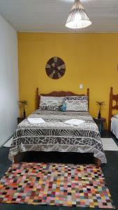 a bedroom with a large bed with a colorful blanket at Guest House Boki da Zezé in Marau