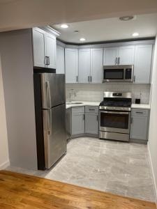 a kitchen with stainless steel appliances and white cabinets at Luxury Apartment 2 Bedrooms and 1 Bathroom in Williams Bridge