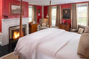 a bedroom with a white bed and a fireplace at Candleberry Inn on Cape Cod in Brewster