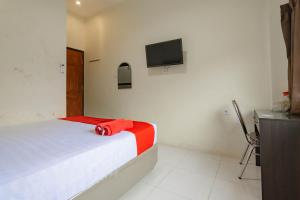 1 dormitorio con 1 cama y TV en la pared en RedDoorz near Arka Sepinggan Airport en Balikpapan