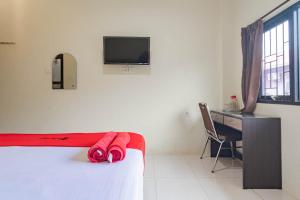 a bedroom with a bed and a desk and a tv at RedDoorz near Arka Sepinggan Airport Balikpapan in Balikpapan