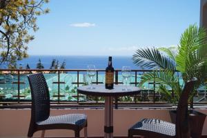 a table with two glasses of wine on a balcony at Tabua Village Madeira Suite VIP in Ribeira Brava