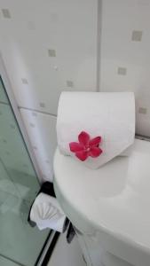 a white toilet with a towel with a pink flower on it at Pousada Azul Atlântica in Guarapari