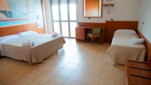 a hotel room with two beds and a desk at Hotel Royal in Giulianova