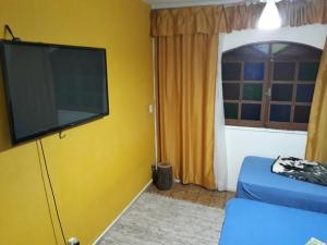 ein Wohnzimmer mit einem Flachbild-TV an einer gelben Wand in der Unterkunft Hostel Gerais in Belo Horizonte