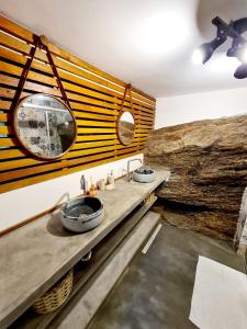 a bathroom with two sinks and a large log wall at Residencial Vilamar in Ilhabela