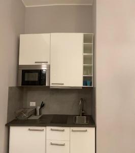 eine Küche mit weißen Schränken, einer Spüle und einer Mikrowelle in der Unterkunft Jr Suite MM3 Repubblica -Stazione-Centro Direz- C3 in Mailand