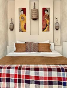 1 dormitorio con 1 cama grande y 3 cuadros en la pared en Apartamentos Caravane, en Tarifa