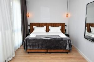 a bedroom with a bed with white sheets and a mirror at Patio Riverfront Aparthotel in Gdańsk