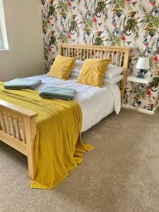 a bedroom with a wooden bed with a yellow blanket on it at Maple House in Bristol
