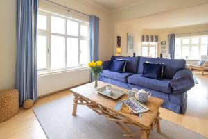 a living room with a blue couch and a table at The Old Bakery - Aldeburgh Coastal Cottages in Aldeburgh