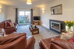 sala de estar con muebles de cuero y chimenea en 4 The Birches - Aldeburgh Coastal Cottages en Aldeburgh