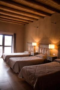 a group of four beds in a room with a window at Hotel Boutique Cañon de Talampaya in Villa Unión