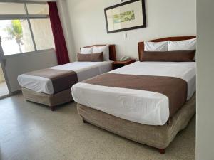 a hotel room with two beds and a window at Hotel Royalty in Veracruz