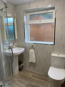 baño con aseo y lavabo y ventana en Pat's Cottage, en Kinawley