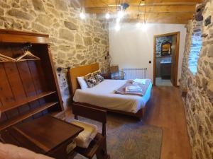 a bedroom with a bed and a stone wall at Fuinhas de Amor in Fornos de Algodres