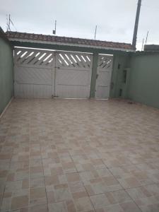an empty garage with two garage doors and a tile floor at Linda casa ! in Mongaguá