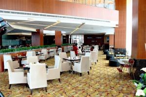 une salle à manger avec des tables, des chaises blanches et une personne dans l'établissement Meritz Hotel, à Miri