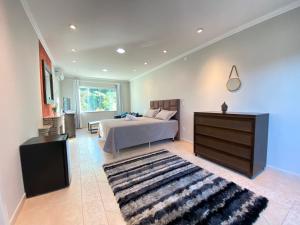 a bedroom with a bed and a dresser and a rug at Pousada Altas Natureza in Florianópolis