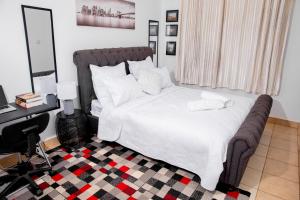 a bedroom with a bed with white sheets and a desk at Retreat Aparthotel-Garden-Solar-Wi-Fi -Firepit-Park-carport in Lusaka