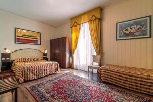 a living room with a bed, chair, table and window at Hotel Villa Romeo in Catania