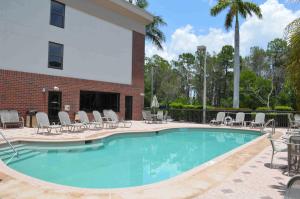 a swimming pool with chairs and a building at Days Inn & Suites by Wyndham Fort Myers Near JetBlue Park in Fort Myers