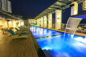 a hotel pool with chairs and a water fountain at Eco Tree Hotel, Melaka in Malacca